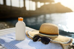 suntan cream bottle and sunglasses on beach towel with sea shore on background-img-blog